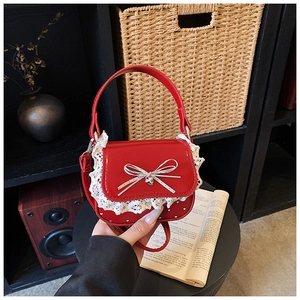 Detailed view of red glossy handbag with white lace trim and sweet heart pendant