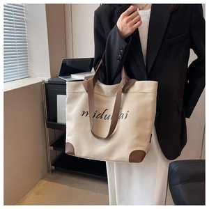 Minimalist canvas tote bag with brown handles carried by a model in a stylish interior
