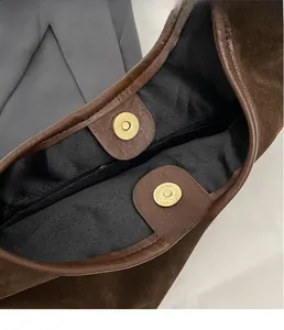 Detailed close-up of the vintage brown suede hobo bag with gold magnetic buckle closure