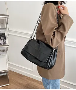 Détail du sac à bandoulière noir avec texture brillante et chaîne en métal élégante