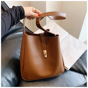 Detail of a brown leather bucket bag with a golden twist lock and premium stitching