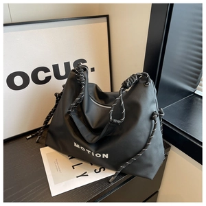 Close-up of black nylon tote bag featuring white MOTION text and rope handle detail
