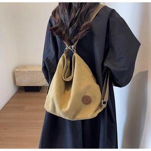 Mustard yellow canvas backpack shown from back on a person wearing a long black coat