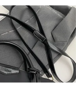 Detail of adjustable leather strap and gold hardware on black oxford tote bag