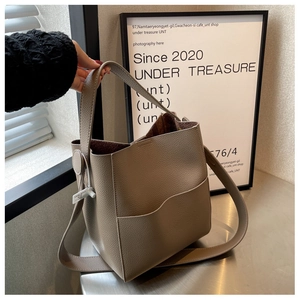 Détail du sac seau taupe avec texture cuir grain litchi et design de poche vague