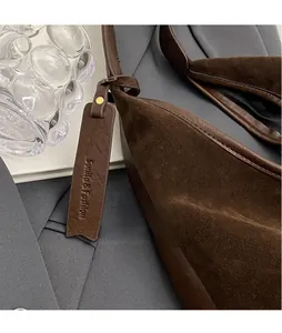 Detail of dark brown matte suede and lychee leather bag with gold rivet and leather tag