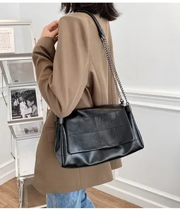 Vue latérale d'un sac à bandoulière noir matelassé avec chaîne porté par un mannequin