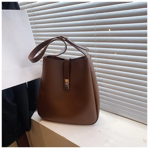 Detail of dark brown leather bucket bag featuring a silver square metal lock and strap