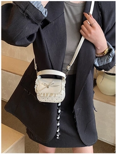 Close-up of white mini lace handbag with black heart print and metallic bow clasp