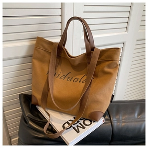Detail of caramel brown canvas tote bag featuring leather handles and adjustable shoulder strap