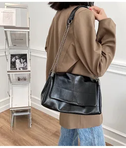 Détail du sac à bandoulière en cuir matelassé noir avec chaîne argentée sur un mannequin