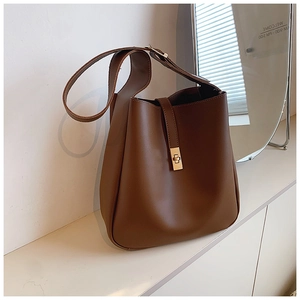 Detail of dark brown leather bucket bag featuring gold twist lock and wide shoulder strap