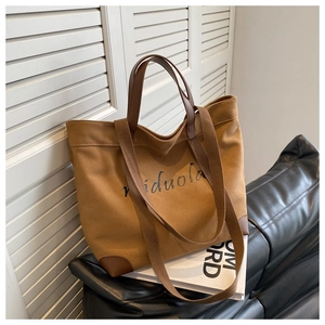 Detail of coffee brown canvas tote bag with black miduola lettering on a leather sofa