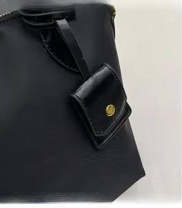 Close-up of black nylon tote bag featuring a square pendant and gold snap button detail