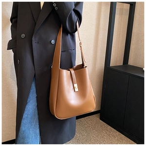 Brown leather bucket bag detail with a metallic golden twist lock and vintage strap design