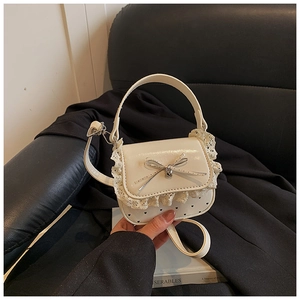 Detail of cream mini bag showing lace trim, leather bow, and embossed heart patterns