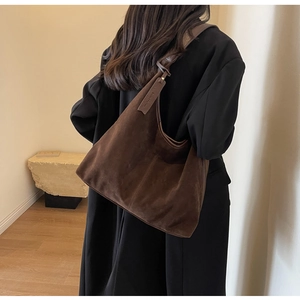 Detail view of large dark brown suede hobo bag with decorative leather tag for daily commute