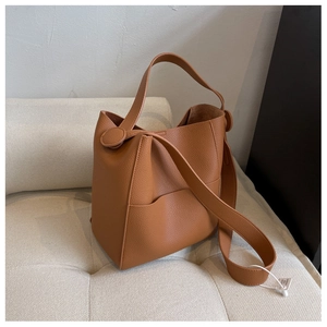 Détail du sac seau en cuir marron avec texture grainée et large bandoulière