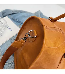 Detail of the high-quality bronze alloy hardware and woven strap on a caramel leather bag