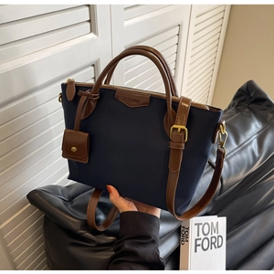 Detail view of navy Oxford fabric tote bag with brown leather handles and gold-tone hardware