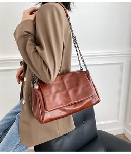 Vue latérale d'un sac à bandoulière matelassé en cuir huilé marron avec chaîne en métal