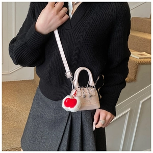 Close-up of pink polka dot shell bag featuring heart plush charm and silver chain detail