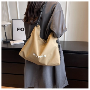 Detail of MOTION logo on khaki nylon tote bag with decorative black and white rope straps
