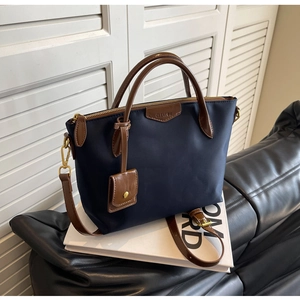 Detail view of Oxford cloth tote with brown leather handles and adjustable shoulder strap