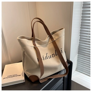 Detail of beige canvas tote with leather corners and dual straps on black cabinet