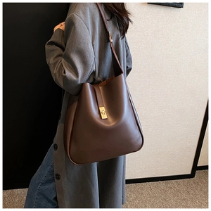 Detail view of brown leather bucket bag with gold buckle and adjustable shoulder strap