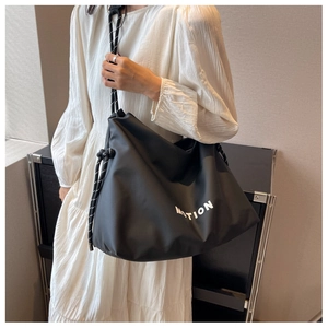 Detail of black nylon tote bag with white MOTION print and woven rope shoulder strap