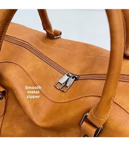 Detail of the smooth metal zipper and textured leather on the brown travel bag