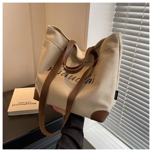 Detail of canvas tote bag with brown leather straps in natural sunlight window view