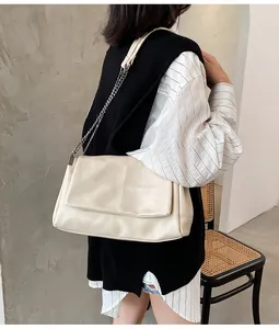 Détail d'un sac bandoulière crème avec rabat à coutures croisées et chaîne en métal
