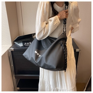 Detail of black nylon tote bag with white lettering and braided rope shoulder straps