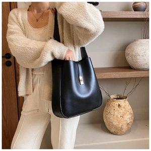 Side view of black leather hobo bag with gold piston clasp on model in minimalist setting
