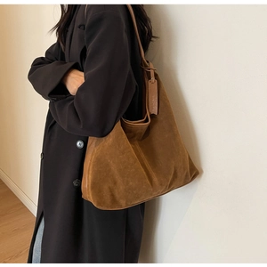 Close-up detail of dark brown suede hobo bag with embossed leather tag and fine texture