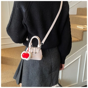 Detail of pink polka dot shell bag with a red heart pendant and chain detail
