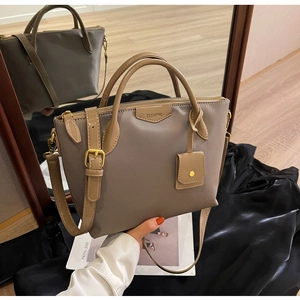 Detailed view of latte brown fabric tote with leather trim and gold metal zipper detail