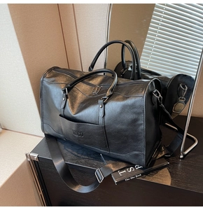 Macro shot of large black leather travel bag with lychee texture and metallic D-ring