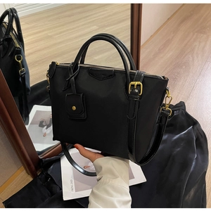 Close-up of black nylon tote bag with golden hardware and small card holder accessory