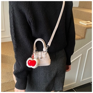 Pink polka dot shell bag with red apple plush charm and fine metal chain detail