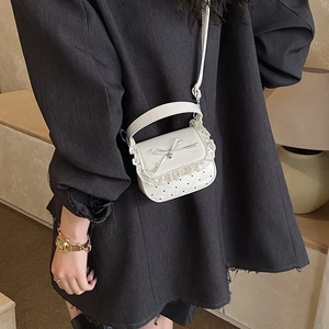 Mini white patent leather bag with sweet lace edges and bow detail on grey suit