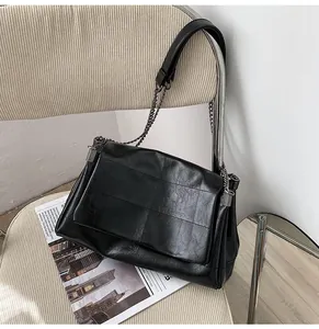 Détail d'un sac à bandoulière en cuir noir matelassé avec chaîne sur une chaise