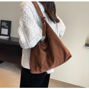 Detail of a large brown suede tote bag with leather strap and decorative stitching