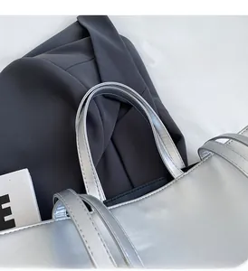 Close-up of silver tote bag showing double flat handles and metallic faux leather texture