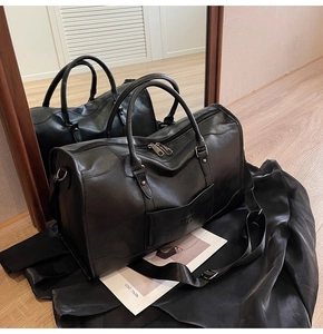 Detail of black leather travel bag with HOCG embossed pocket and adjustable shoulder strap