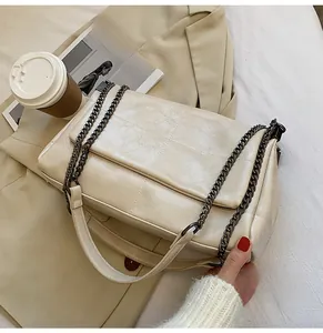 Gros plan du sac à chaîne matelassé beige avec détails métalliques en décor urbain