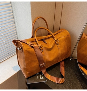 Close-up of brown faux leather travel bag with adjustable strap and metal hardware details