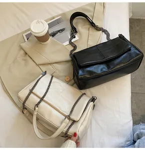 Sacs à bandoulière matelassés chics en noir et beige posés sur un couvre-lit beige